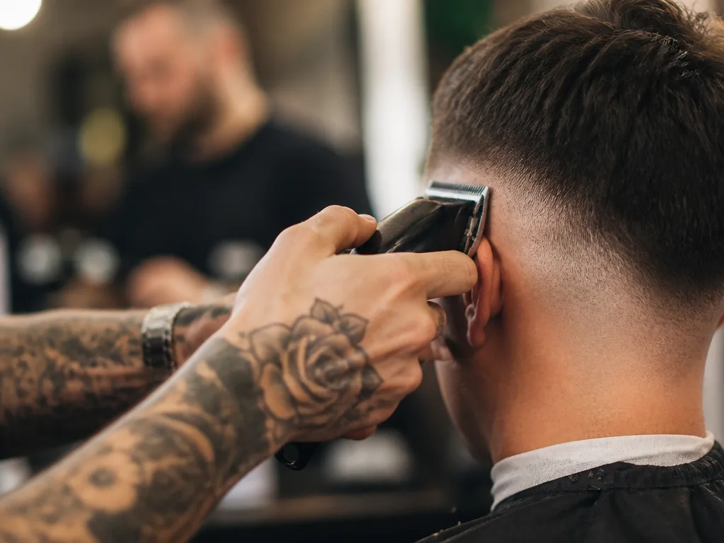 Frisör klipper fade med maskin i modern barbershop, editorial stilleben